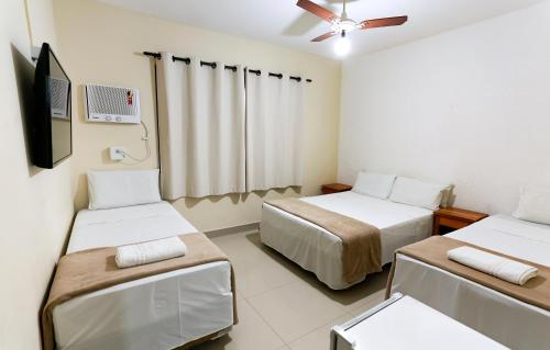 a room with two beds and a flat screen tv at Indaiá Praia Hotel in Bertioga