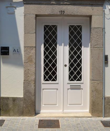 a white door in a stone building with a sign at Glamour Guest House in Viana do Castelo