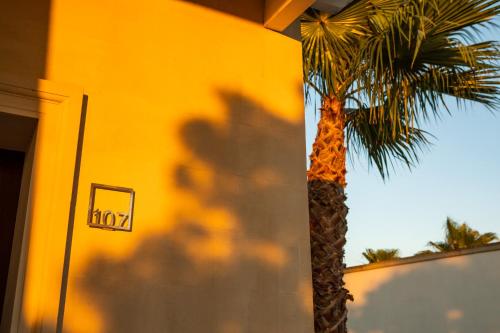 a palm tree next to a yellow building with a sign at Giardino Dei Pini - Boutique Hotel in Alliste