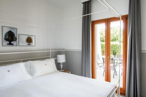 a bedroom with a white bed and a balcony at Giardino Dei Pini - Boutique Hotel in Alliste