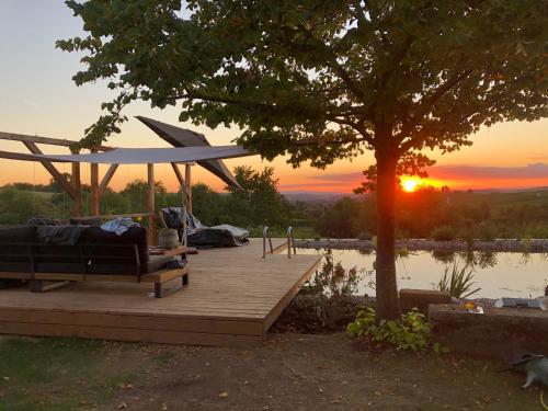 a bench on a wooden deck with a tree and the sunset at The view in Ilsfeld