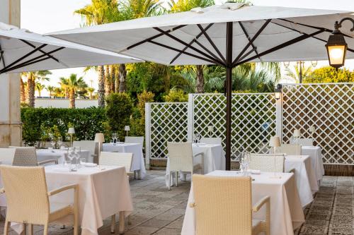 a restaurant with white tables and chairs and umbrellas at Giardino Dei Pini - Boutique Hotel in Alliste