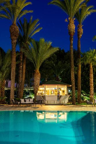a pool with palm trees in front of a house at Giardino Dei Pini - Boutique Hotel in Alliste