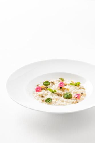 a white bowl of risotto on a white background at Giardino Dei Pini - Boutique Hotel in Alliste