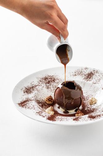 a person is pouring chocolate on a plate at Giardino Dei Pini - Boutique Hotel in Alliste