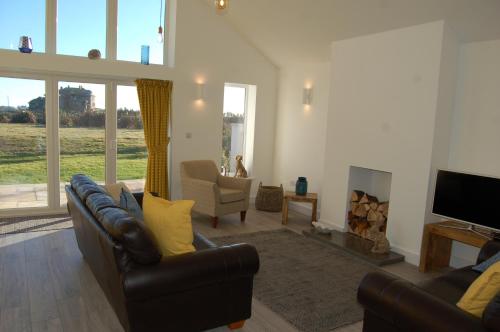 a living room with two leather couches and a fireplace at Beautiful, Modern Villa 5 mins walk from the Stunning Bay at Trearddur in Holyhead