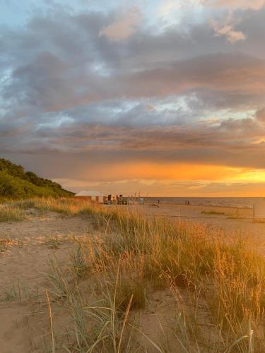a beach at sunset with people standing on the sand at Apartment near the seaside in Jūrmala