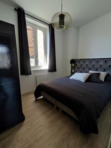 a bedroom with a bed with a black comforter and two windows at LE REFLET DES VOILES FACE AU PORT DE FECAMP in Fécamp