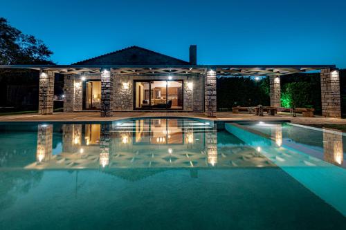 a swimming pool in front of a house at night at Kymaros Villas in Keri
