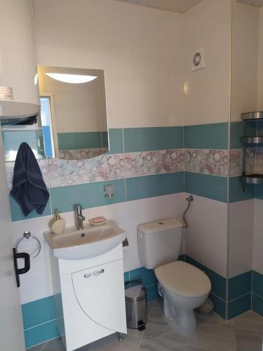 a bathroom with a toilet and a sink and a mirror at Апартамент Blue apartment, гр. Китен in Kiten
