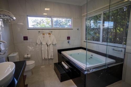 a bathroom with a tub and a toilet and a sink at Ananda Pousada in Pirenópolis