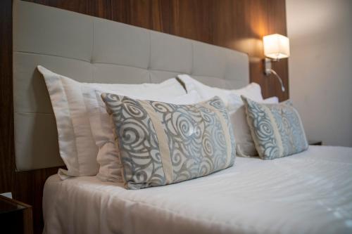 a bed with white pillows and a headboard at Ananda Pousada in Pirenópolis