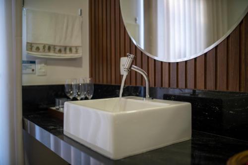 a white sink in a bathroom with wine glasses at Ananda Pousada in Pirenópolis