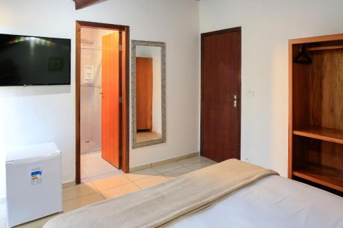 a bedroom with a bed and a tv and a mirror at Indaiá Praia Hotel in Bertioga