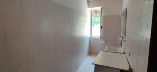 ein weißes Bad mit einem Waschbecken und einem Fenster in der Unterkunft Villa Fiorita in Sprazzi