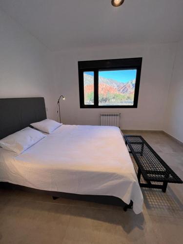sypialnia z dużym białym łóżkiem i oknem w obiekcie Casita de Purmamarca w mieście Purmamarca