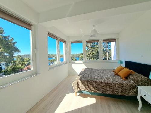 a bedroom with white walls and windows and a bed at A2D1 Mali Losinj in Mali Lošinj