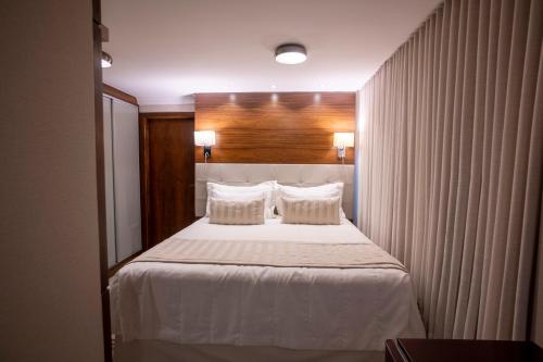 a bedroom with a large white bed with two pillows at Ananda Pousada in Pirenópolis