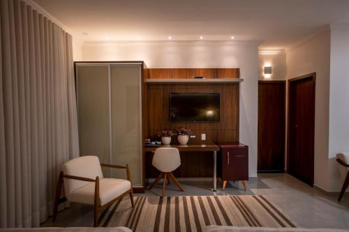 a hotel room with a desk and a tv and chairs at Ananda Pousada in Pirenópolis