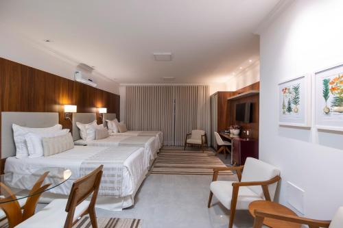 a hotel room with two beds and a table and chairs at Ananda Pousada in Pirenópolis