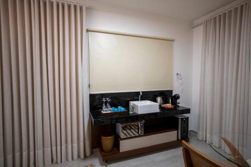a bathroom with a sink and a window with curtains at Ananda Pousada in Pirenópolis