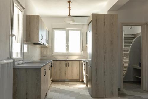 a kitchen with wooden cabinets and a large window at The Tree Houses Santorini in Perissa