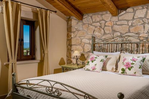 a bedroom with a bed and a stone wall at Kymaros Villas in Keri