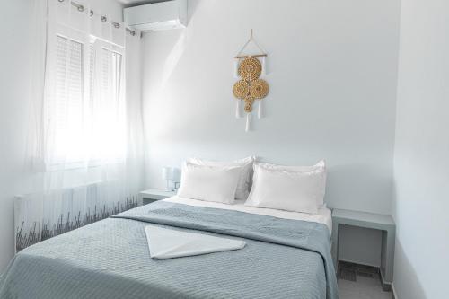 a white bedroom with a bed with a laptop on it at The Tree Houses Santorini in Perissa