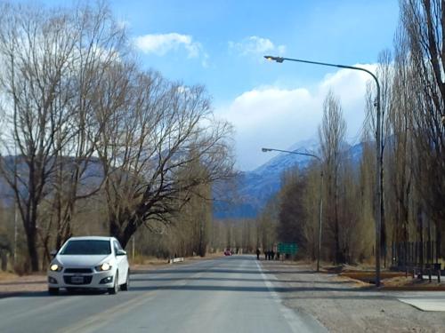 a white car driving down a road with mountains in the background at Cabaña Loft La Ribera in Maipú