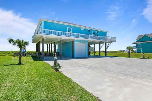 a blue house with a balcony and a driveway at 4 Biscayne home in Bolivar Beach