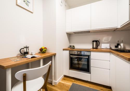 - une cuisine avec des placards blancs et une chaise blanche dans l'établissement Rent like home - Gwiaździsta 20, à Wrocław
