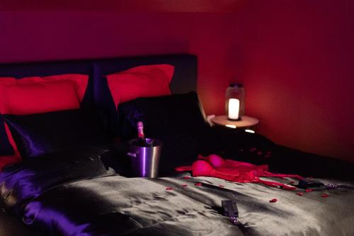 a dark room with a bed with red walls at L'écrin des secrets in Villeperdue
