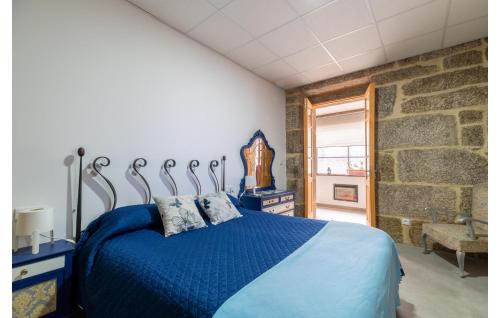 a bedroom with a blue bed and a stone wall at Beautiful Apartment In A Arnoia in Arnoia