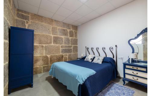 a bedroom with a blue bed and a stone wall at Beautiful Apartment In A Arnoia in Arnoia