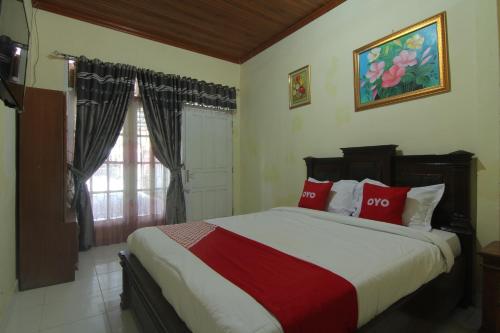 a bedroom with a bed with red pillows and a window at Penginapan Bunga Sonsang Padang Syariah in Tabing