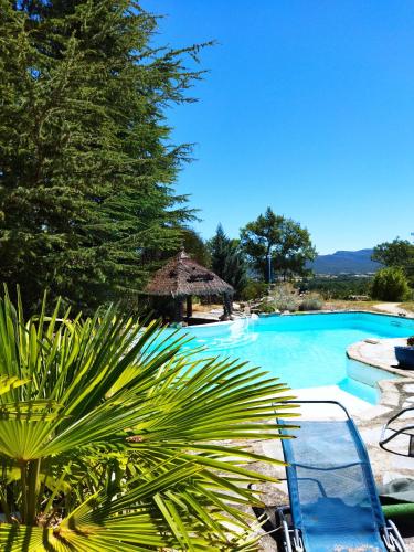 une grande piscine bleue avec une hacienda dans l'établissement La Chaumière magique des Elfes et ses énigmes, à Servas