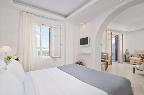 a white bedroom with a bed and a living room at Stelia Mare Boutique Hotel in Naousa