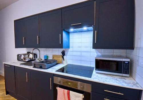 a kitchen with black cabinets and a microwave at A Stones Throw By My Getaways in Brighton & Hove