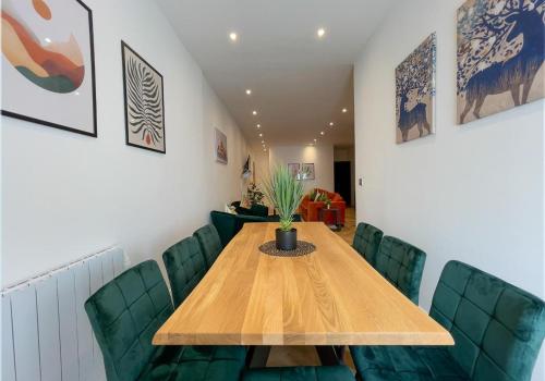 Un comedor con una mesa de madera y sillas verdes. en A Stones Throw By My Getaways, en Brighton & Hove
