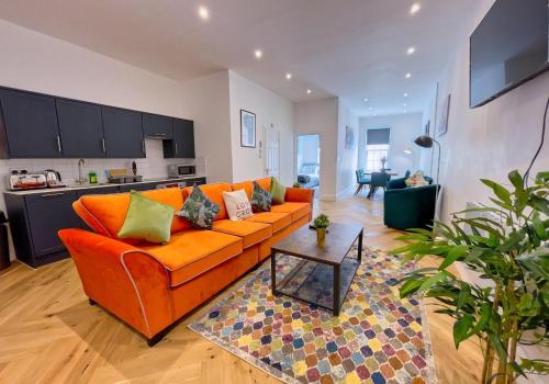 a living room with an orange couch and a kitchen at A Stones Throw By My Getaways in Brighton & Hove