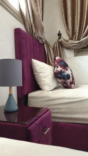 艾茲魯的住宿－Maison GHITA，一张带紫色沙发的床和一张带台灯的桌子