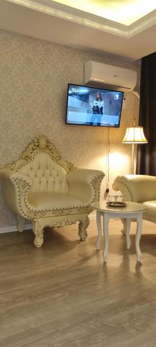 a living room with a couch and a tv on the wall at Grand Hotel Baroc in Zalău