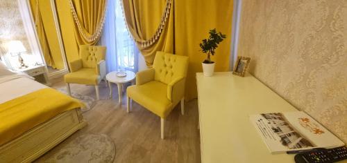 a bedroom with a bed and two chairs and a table at Grand Hotel Baroc in Zalău
