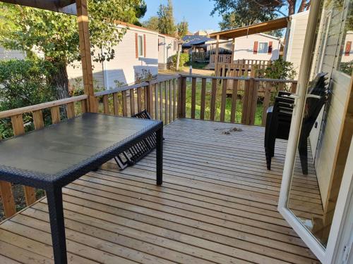 a wooden porch with a table on a deck at Mobil home - Clim, TV - Camping '4 étoiles' - Narbonne Plage - 014 in Narbonne-Plage