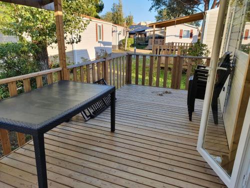 - une terrasse couverte en bois avec une table dans l'établissement Mobil-home Clim, TV - Camping Narbonne-Plage 4 étoiles - MH-A015, à Narbonne-Plage