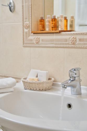 a bathroom sink with a faucet and a basket of soap at Stelia Mare Boutique Hotel in Naousa