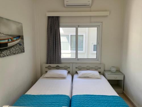 Dos camas en una habitación pequeña con ventana. en Themis Beach Apartments, en Lárnaca