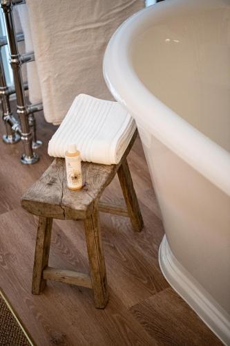 a stool next to a bath tub next to a toilet at The Cotley Inn in Wambrook