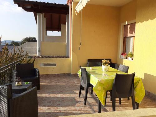 eine Terrasse mit einem Tisch und Stühlen sowie ein gelbes Haus in der Unterkunft B&B ANNA in Piscinas