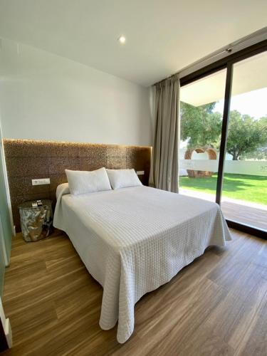 a bedroom with a white bed with a large window at VISTA LAGO VILLE in Chiclana de la Frontera